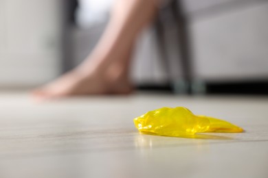 Photo of Unrolled condom on floor indoors, closeup with space for text. Safe sex