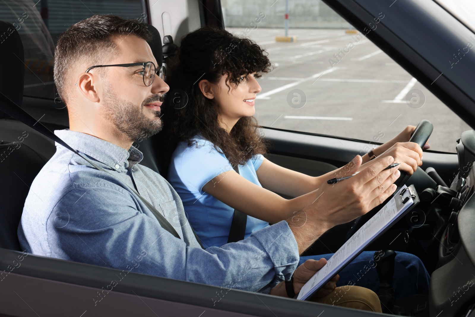 Photo of Driving school. Happy student passing driving test with examiner in car at parking lot