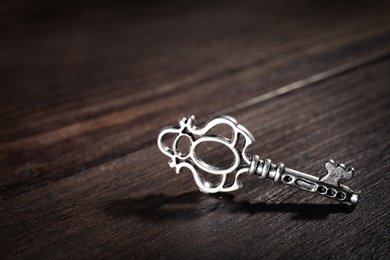 Photo of Old vintage key on wooden background, space for text