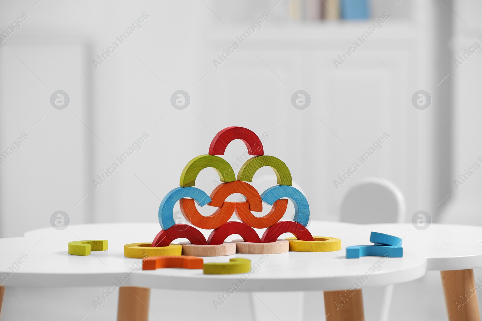 Photo of Colorful wooden pieces of playing set on white table indoors. Educational toy for motor skills development