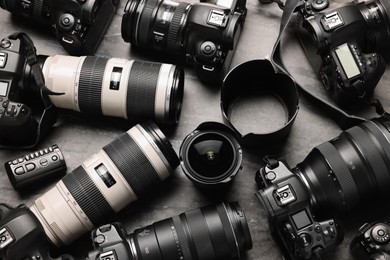 Modern cameras on dark gray marble table, flat lay