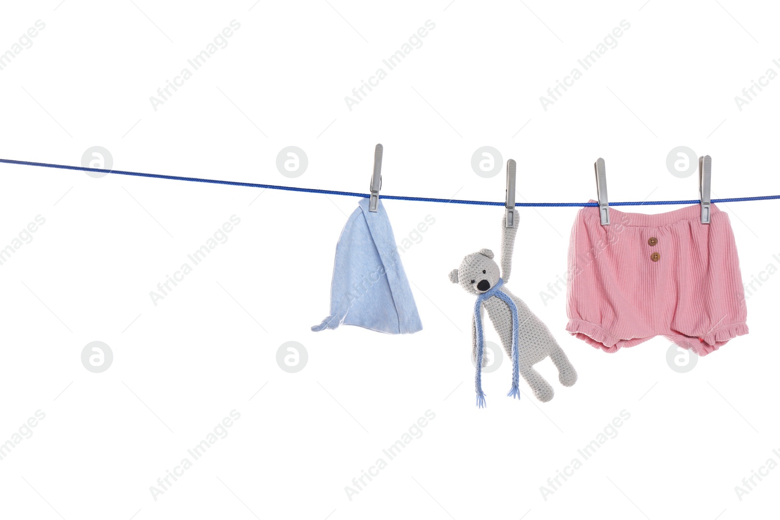 Photo of Baby clothes and toy bear drying on laundry line against white background