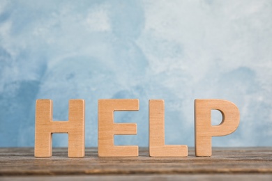 Photo of Word "Help" on wooden table against color background