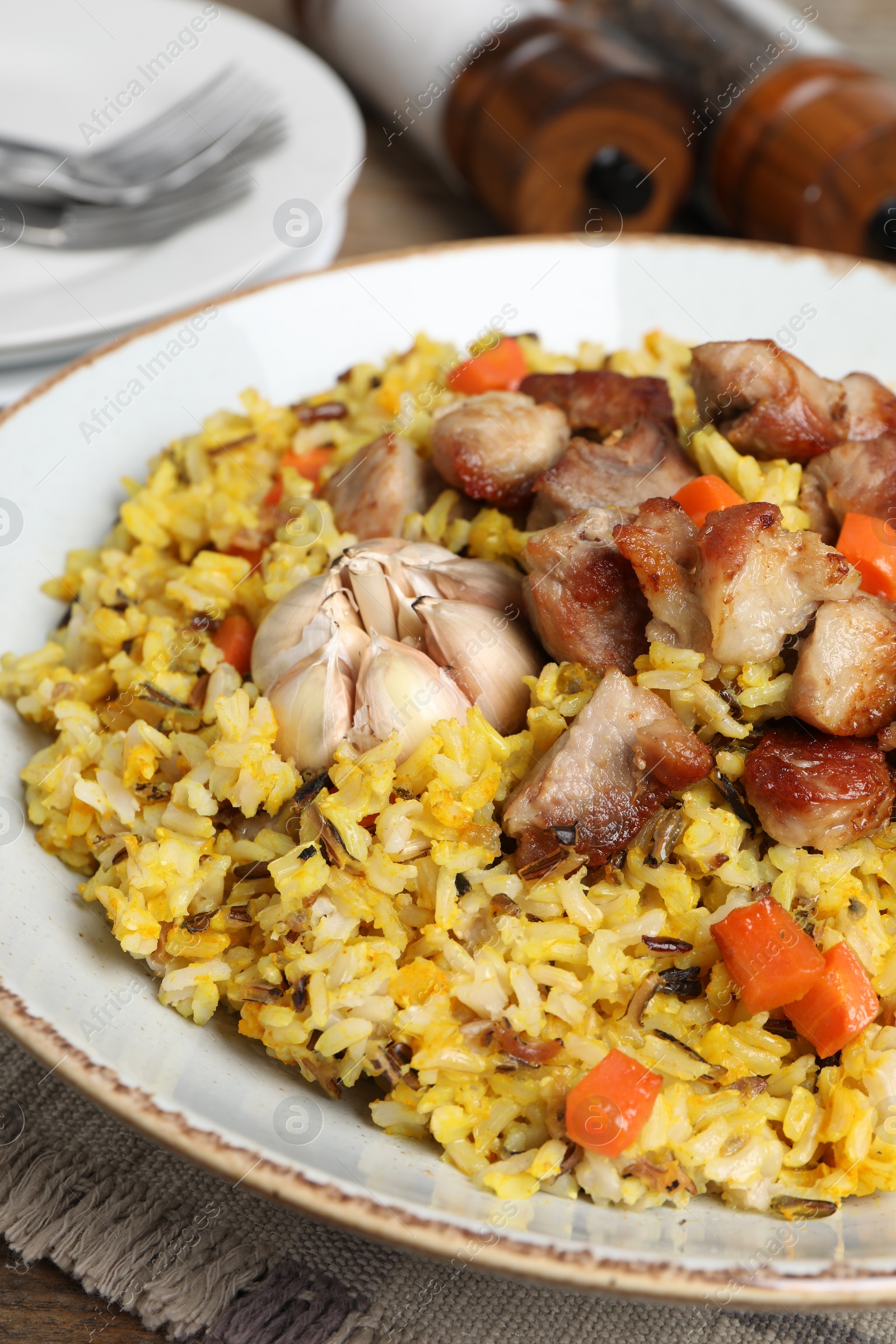 Photo of Delicious pilaf with meat, carrot and garlic on table, closeup