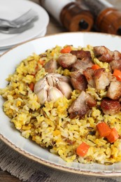 Photo of Delicious pilaf with meat, carrot and garlic on table, closeup