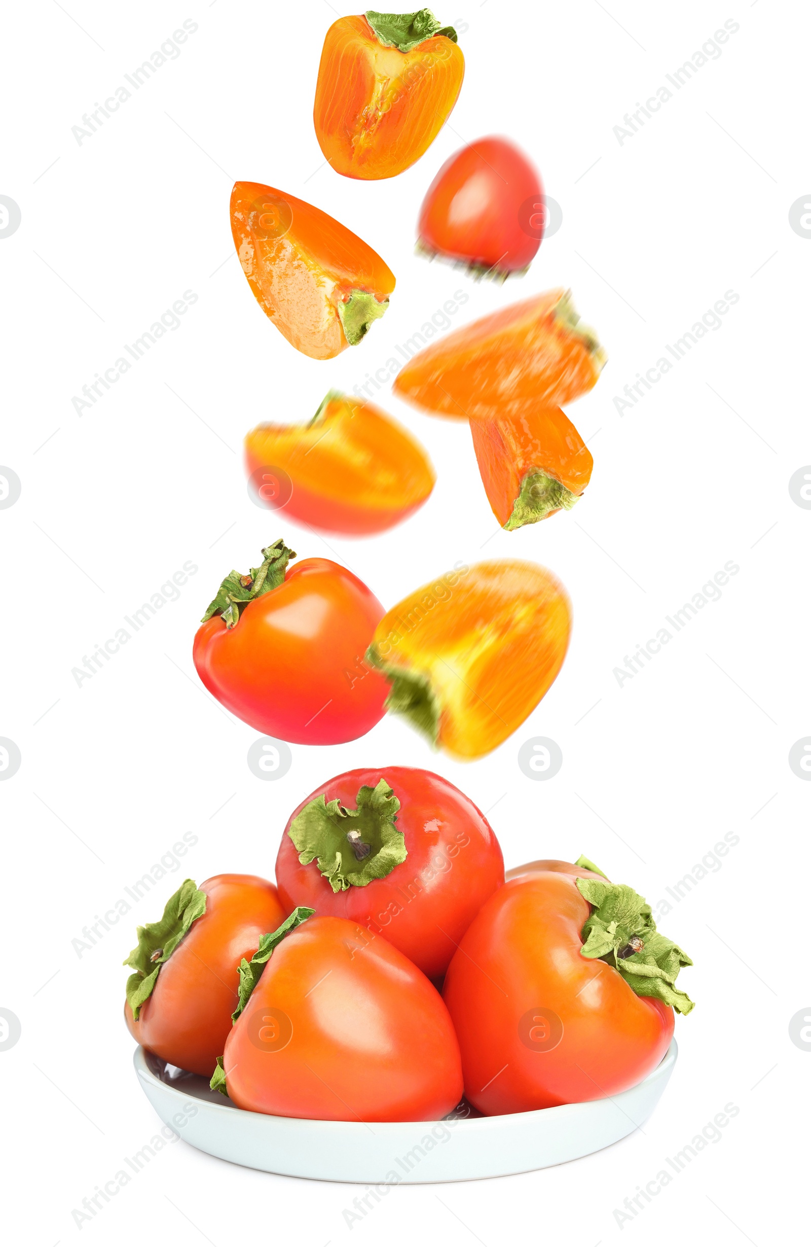 Image of Sweet ripe persimmons falling into bowl on white background