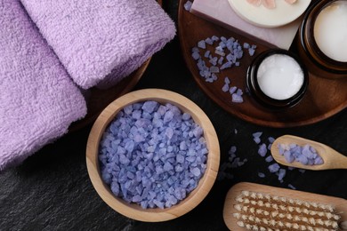 Flat lay composition with different spa products and lavender on black textured table