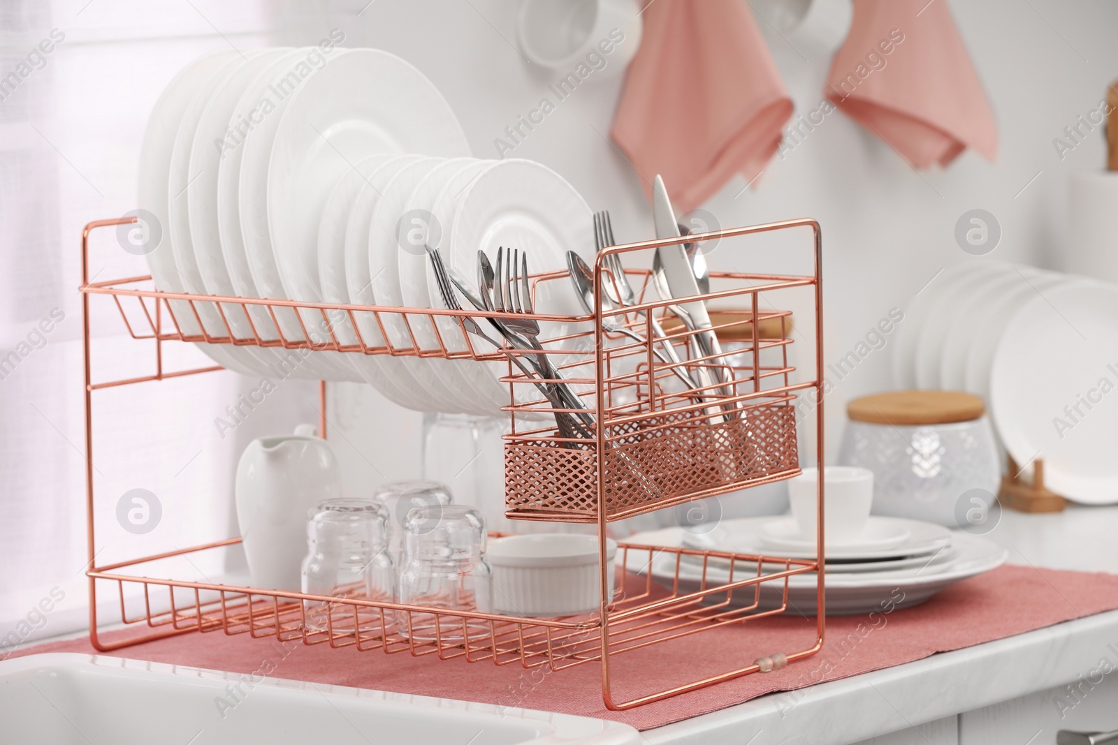 Photo of Drying rack with clean dishes and cutlery on countertop in kitchen