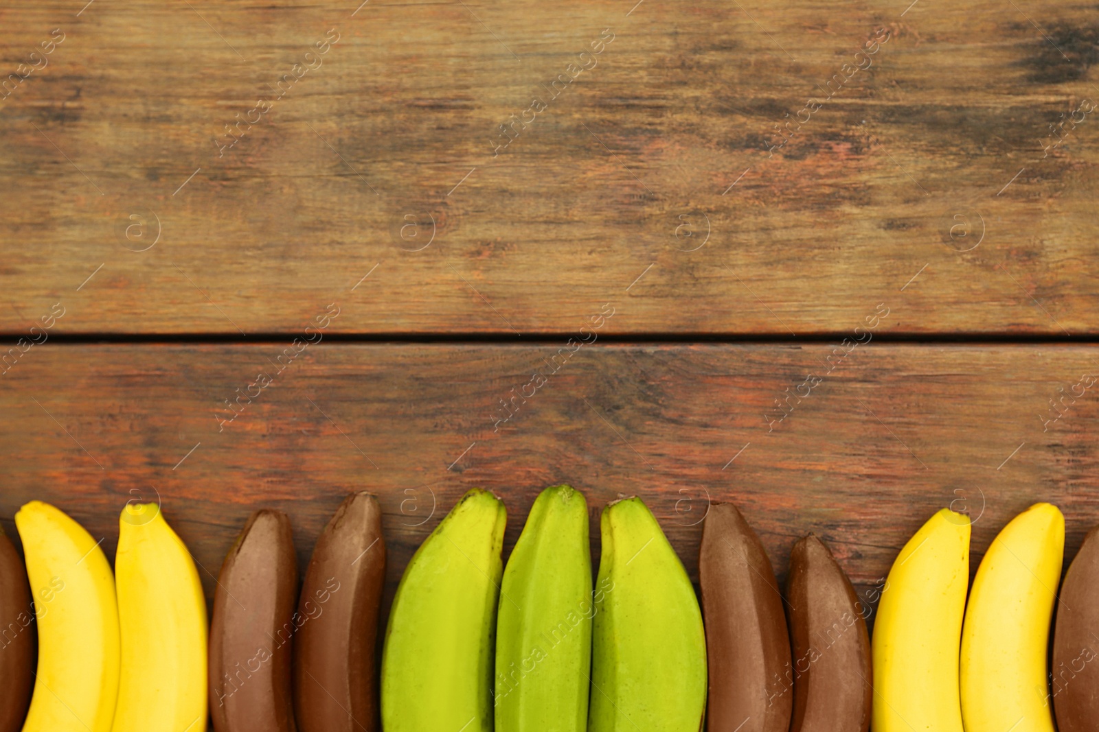 Photo of Many different bananas on wooden table, flat lay. Space for text