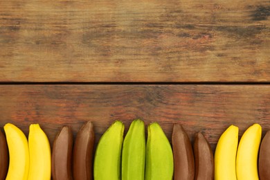 Photo of Many different bananas on wooden table, flat lay. Space for text