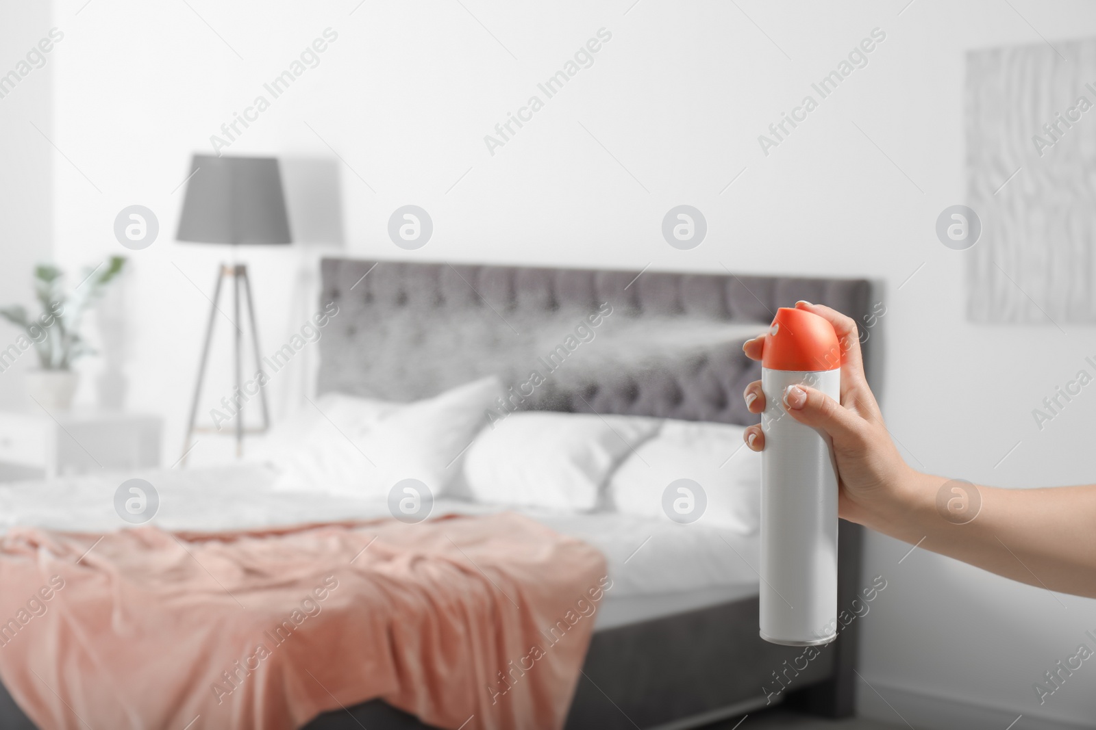 Photo of Woman spraying air freshener in bedroom