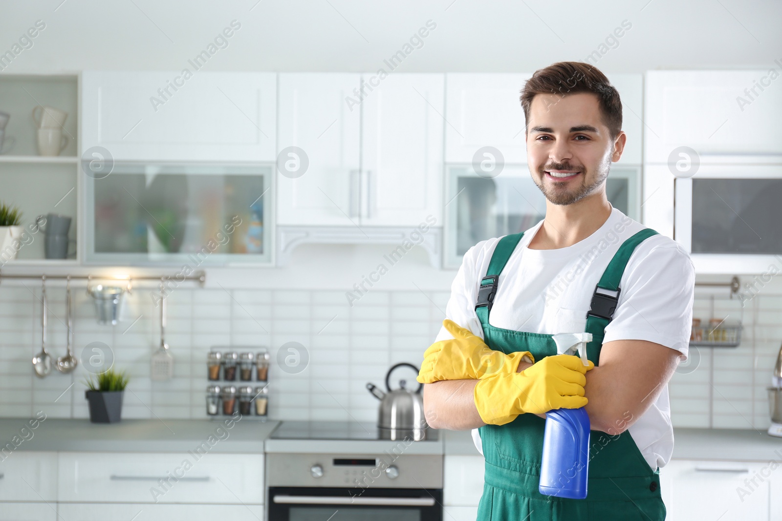 Photo of Portrait of janitor with sprayer in kitchen. Cleaning service