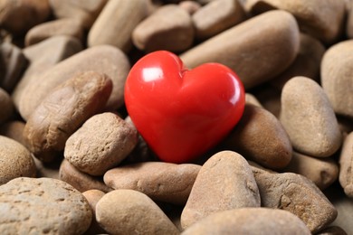 Photo of One red decorative heart on stones, closeup