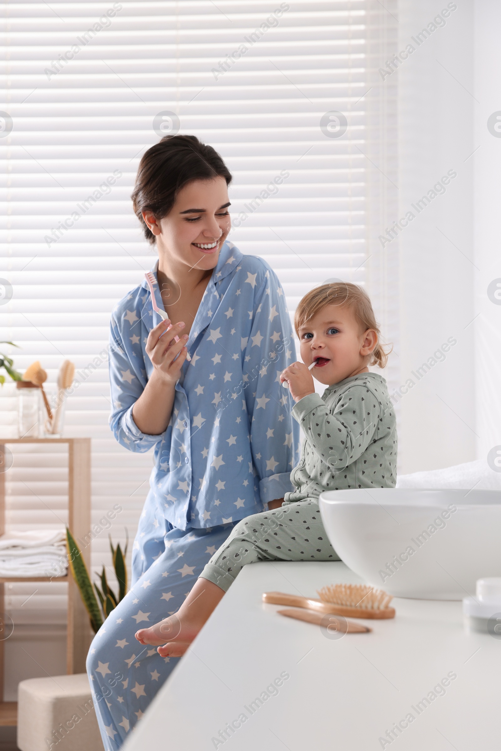 Photo of Mother and her daughter brushing teeth together in bathroom