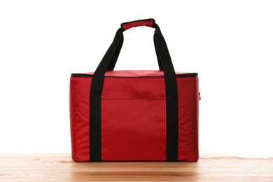 Modern red thermo bag on wooden table against white background