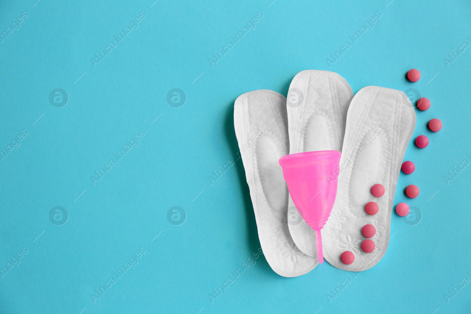 Photo of Flat lay composition with menstrual pads, cup and pills on color background. Gynecological care