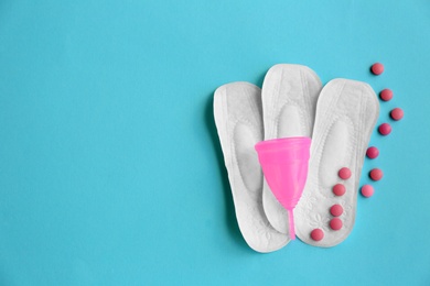 Flat lay composition with menstrual pads, cup and pills on color background. Gynecological care