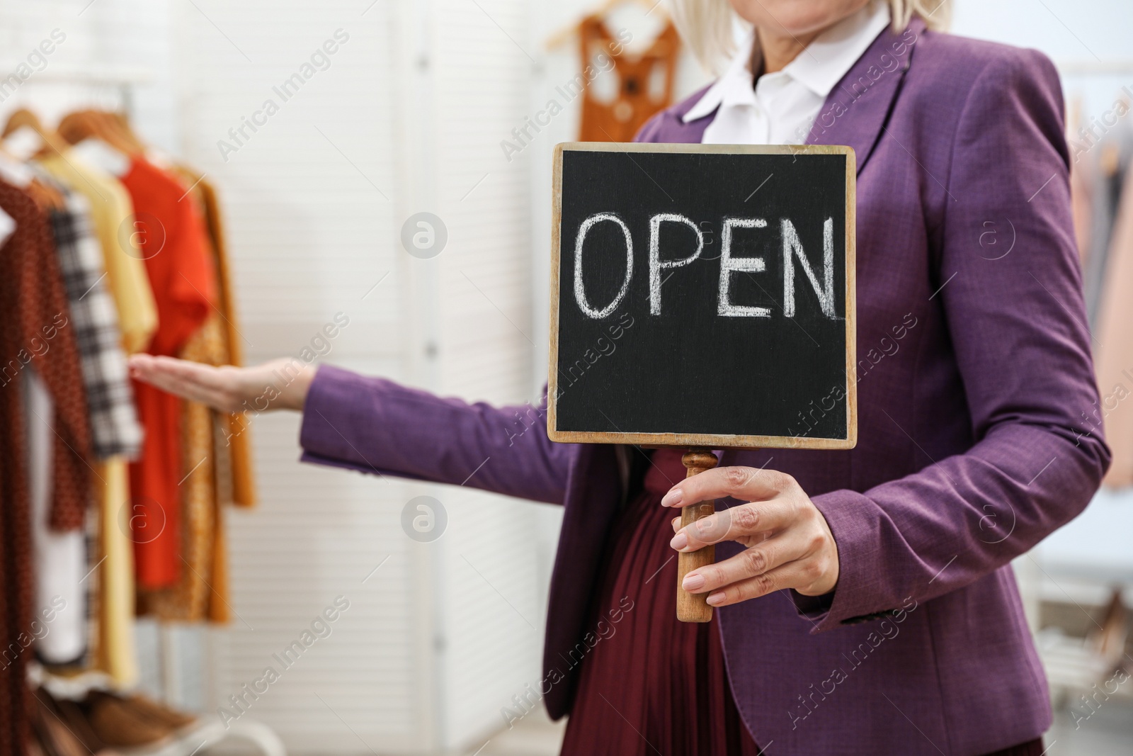 Photo of Female business owner holding OPEN sign in boutique, closeup