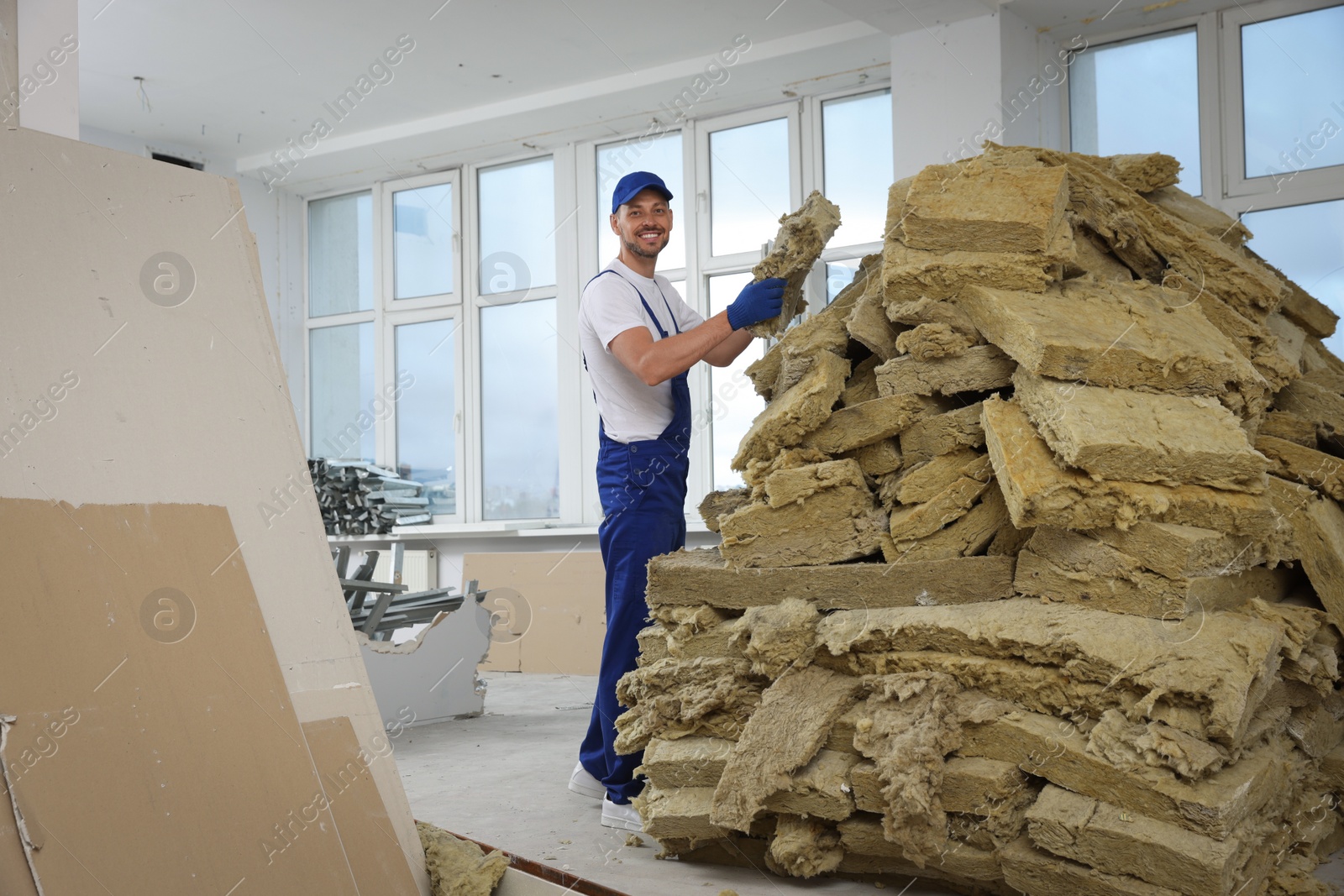 Photo of Construction worker with used glass wool in room prepared for renovation