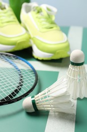 Photo of Feather badminton shuttlecocks, rackets and sneakers on court, closeup