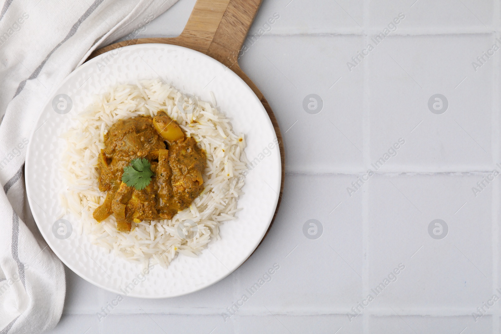 Photo of Delicious chicken curry with rice on white tiled table, top view. Space for text