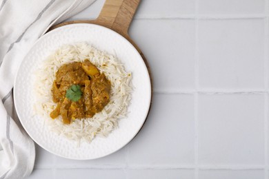 Photo of Delicious chicken curry with rice on white tiled table, top view. Space for text