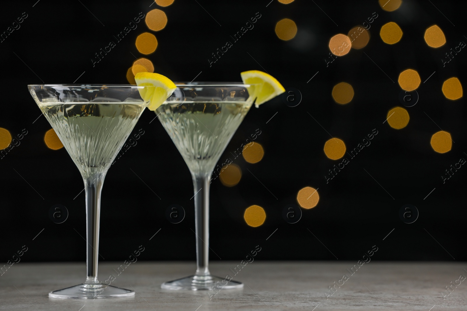 Photo of Martini glasses of refreshing cocktails with lemon slices on light grey table, space for text