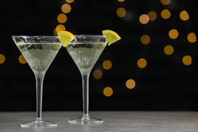 Martini glasses of refreshing cocktails with lemon slices on light grey table, space for text