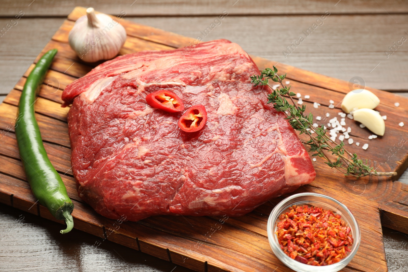 Photo of Fresh raw beef cut with spices on wooden table