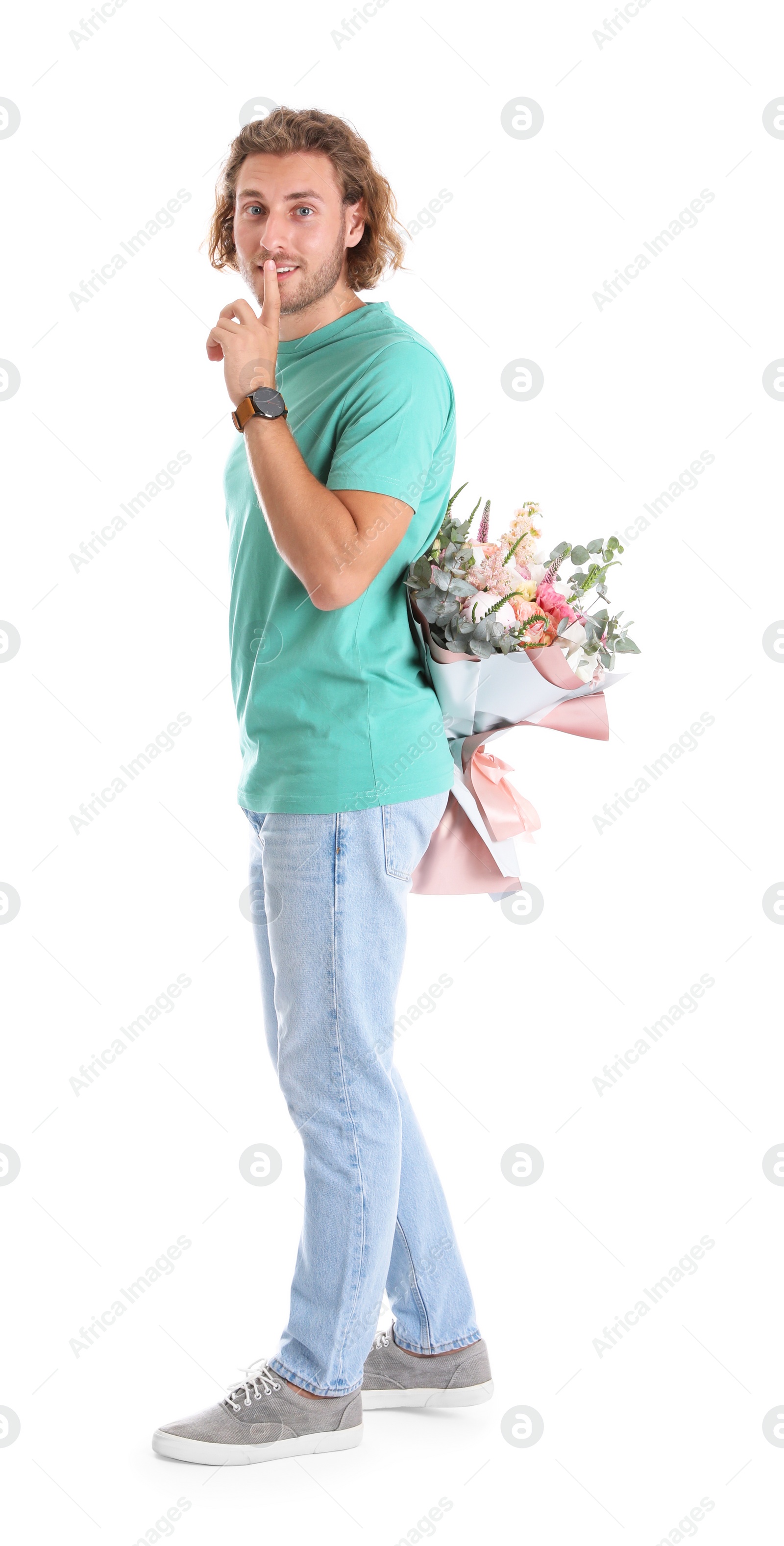 Photo of Young handsome man hiding beautiful flower bouquet behind his back on white background