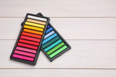 Colorful pastels in trays on white wooden table, space for text. Drawing materials