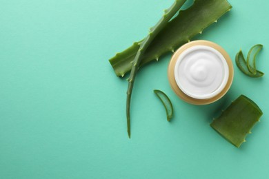 Jar of natural cream and aloe leaves on green background, flat lay. Space for text