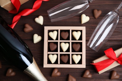 Photo of Flat lay composition with heart shaped chocolate candies on wooden table. Happy Valentine's day
