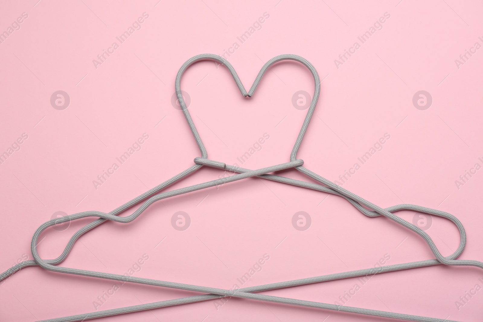 Photo of Two hangers on pink background, top view