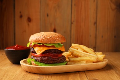 Photo of Tasty cheeseburger with patties, sauce and French fries on wooden table