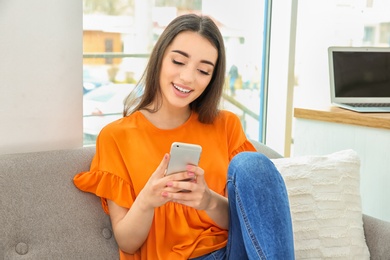 Photo of Attractive young woman using mobile phone at home