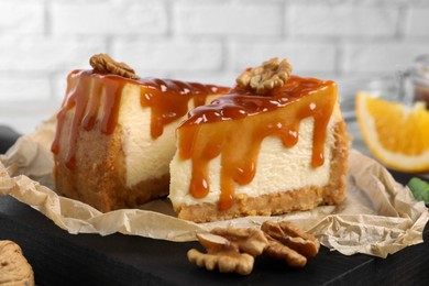Photo of Pieces of delicious caramel cheesecake with walnuts on table, closeup