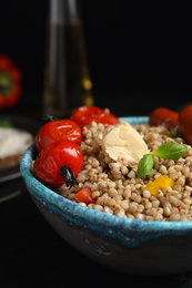 Photo of Tasty buckwheat porridge with sausages in bowl, closeup