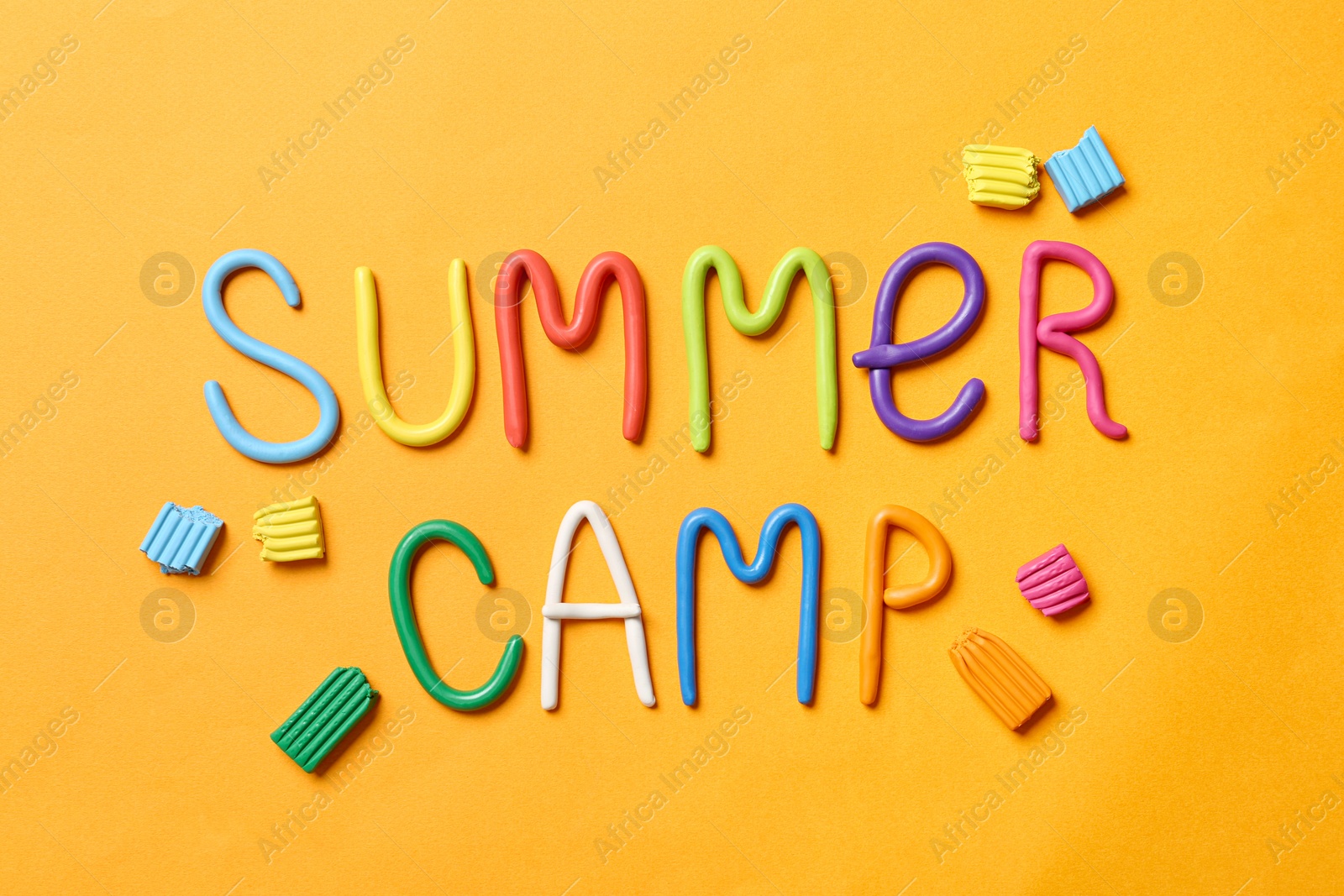 Photo of Text SUMMER CAMP made of modelling clay on color background, flat lay