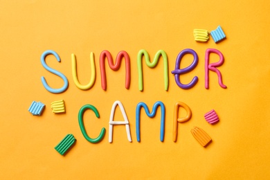 Text SUMMER CAMP made of modelling clay on color background, flat lay