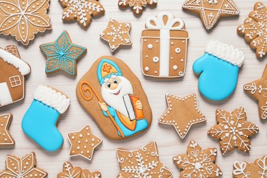 Tasty gingerbread cookies on white wooden table, flat lay. St. Nicholas Day celebration