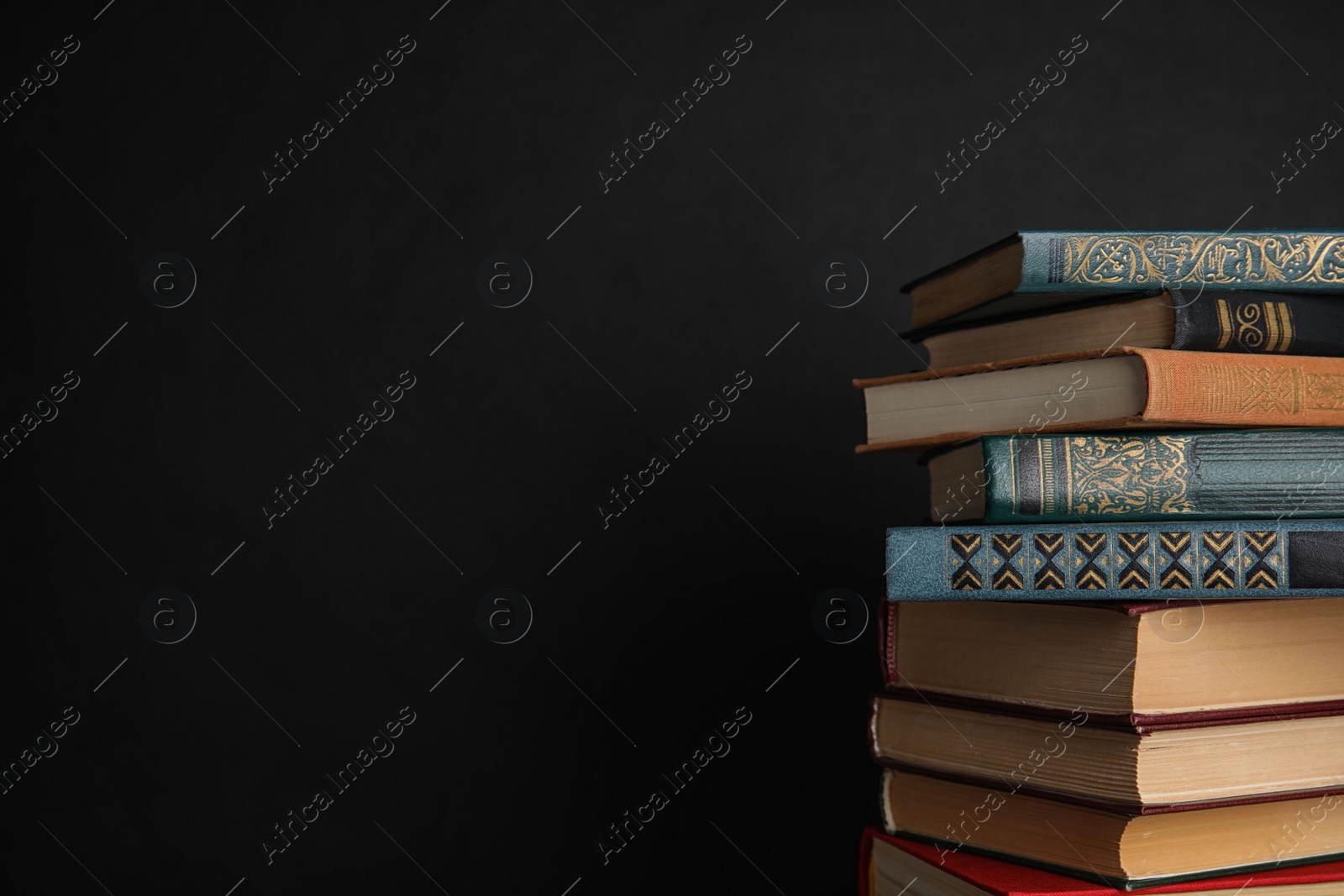 Photo of Stack of hardcover books on black background. Space for text