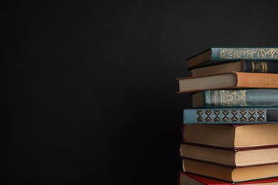 Photo of Stack of hardcover books on black background. Space for text