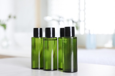 Mini bottles with cosmetic products on white table in bathroom