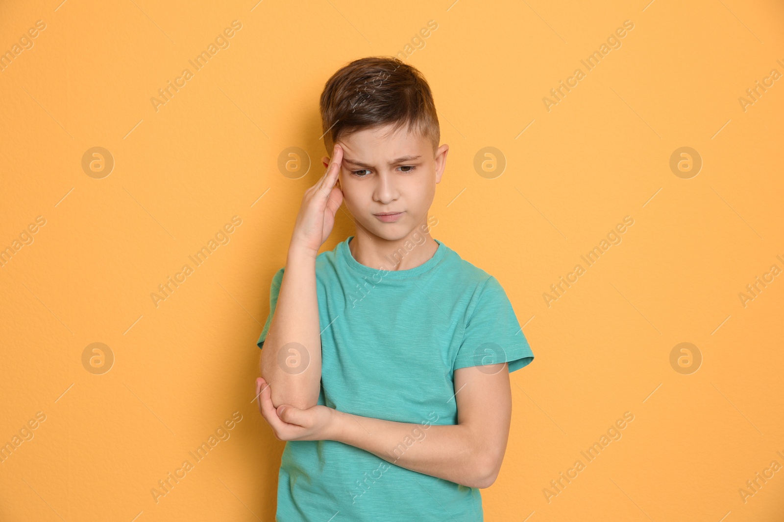 Photo of Little boy suffering from headache on color background