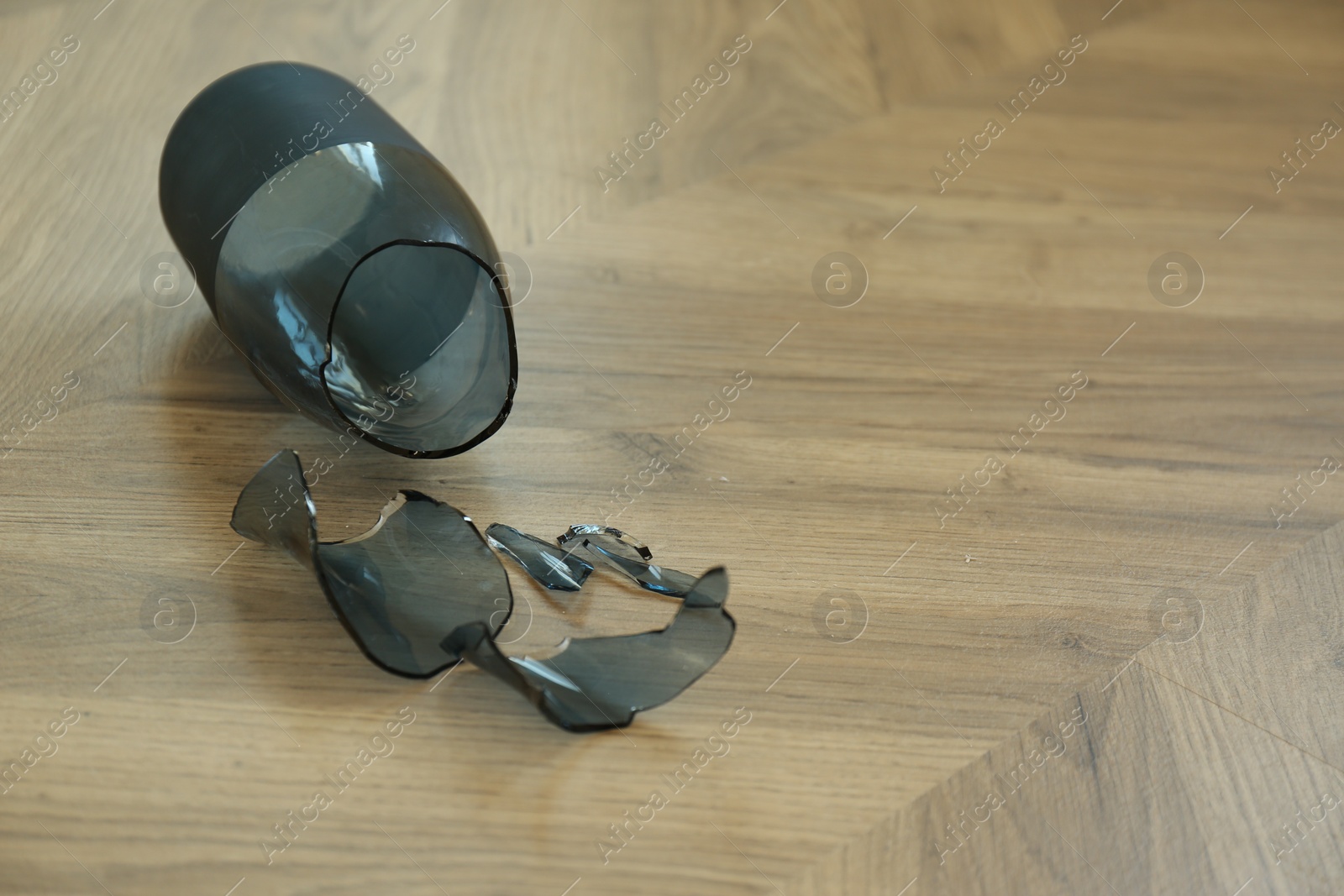 Photo of Broken blue glass vase on wooden floor. Space for text