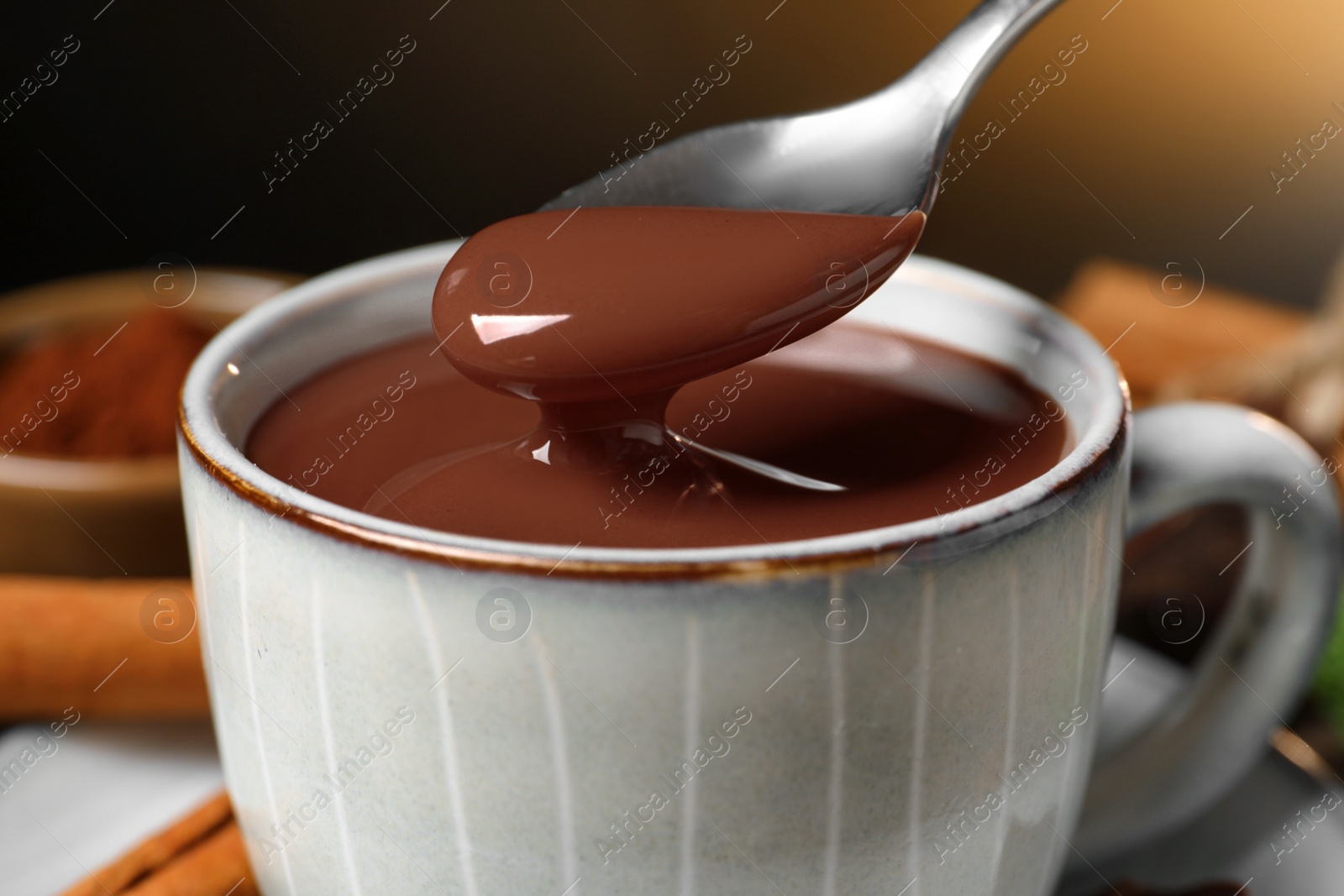 Photo of Spoon with yummy hot chocolate over cup, closeup