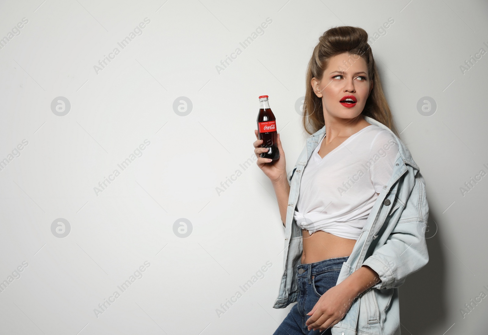 Photo of MYKOLAIV, UKRAINE - NOVEMBER 28, 2018: Young woman with bottle of Coca-Cola on white background, space for text