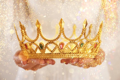 Image of Fantasy world. Woman holding beautiful golden crown, closeup