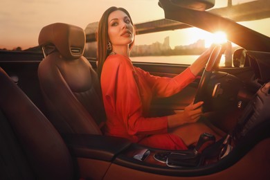 Photo of Sexy woman driving luxury convertible car at sunset
